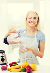Image showing smiling woman with blender preparing shake at home