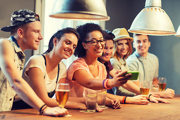 Image showing happy friends with smartphone taking selfie at bar