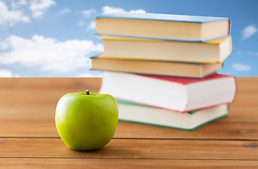 Image showing close up of books and green apple on wooden table