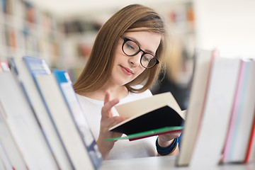 Image showing portrait of famale student selecting book to read in library