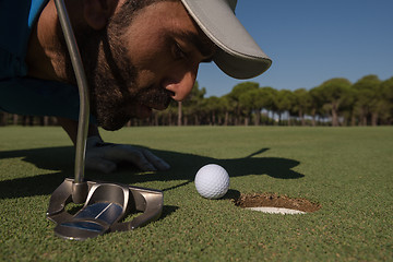 Image showing golf player blowing ball in hole