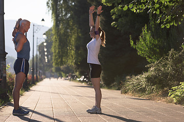 Image showing couple warming up and stretching before jogging