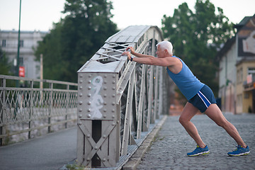 Image showing handsome man stretching before jogging