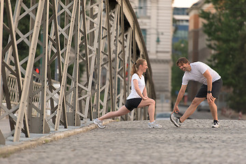 Image showing couple warming up and stretching before jogging