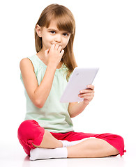 Image showing Young girl is using tablet while sitting on floor