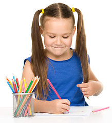 Image showing Little girl is drawing using pencils