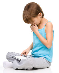 Image showing Young girl is using tablet while sitting on floor