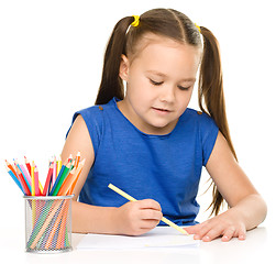 Image showing Little girl is drawing using pencils