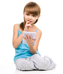 Image showing Young girl is using tablet while sitting on floor