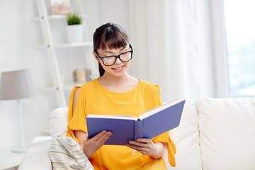 Image showing smiling young asian woman reading book at home