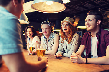 Image showing happy friends drinking beer and talking at bar