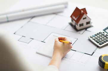 Image showing close up of hand on blueprint writing to notebook