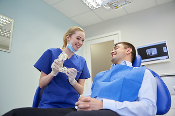 Image showing happy dentist showing jaw layout to male patient