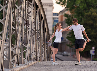 Image showing couple warming up and stretching before jogging