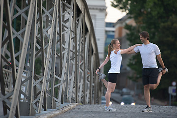 Image showing couple warming up and stretching before jogging