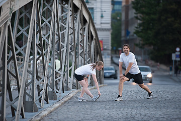 Image showing couple warming up and stretching before jogging