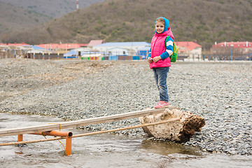 Image showing  A five-year girl is undecided at the end of the plank thrown across a stream