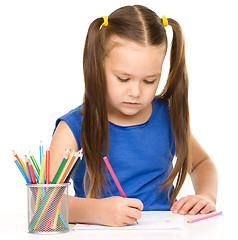 Image showing Little girl is drawing using pencils