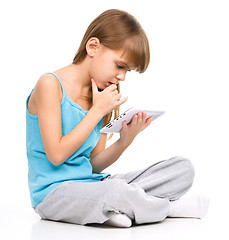 Image showing Young girl is using tablet while sitting on floor