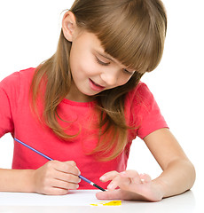 Image showing Little girl is painting with gouache