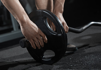 Image showing Man preparing barbell at gym class