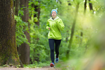 Image showing Sporty young female runner in the forest. 