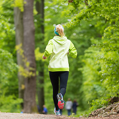 Image showing Sporty young female runner in the forest. 