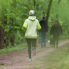 Image showing Sporty young female runner in the forest. 