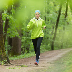 Image showing Sporty young female runner in the forest. 