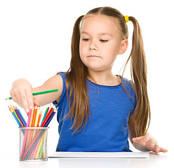 Image showing Little girl is drawing using pencils