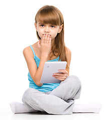 Image showing Young girl is using tablet while sitting on floor