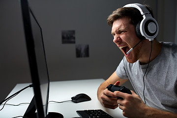 Image showing man in headset playing computer video game at home