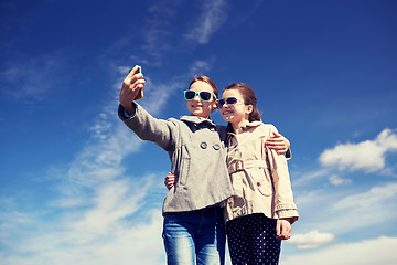 Image showing happy girls with smartphone taking selfie outdoors