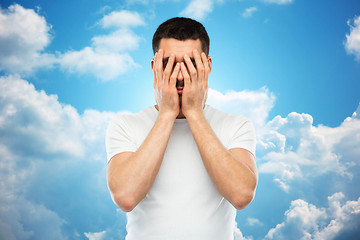 Image showing man in white t-shirt covering his face with hands