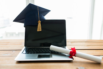 Image showing close up of laptop with mortarboard and diploma