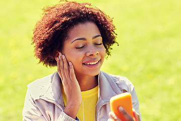 Image showing happy african woman with smartphone and earphones