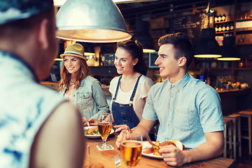 Image showing happy friends eating and drinking at bar or pub