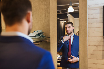 Image showing man trying tie on at mirror in clothing store