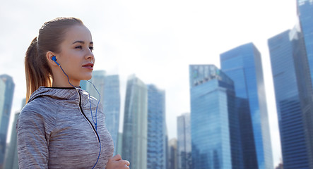 Image showing happy woman with earphones running in city