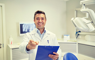 Image showing happy dentist pointing to you at dental clinic