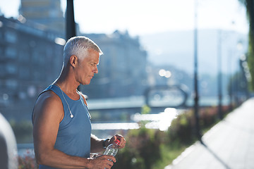 Image showing senior jogging man drinking fresh water from bottle