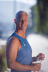 Image showing senior jogging man drinking fresh water from bottle