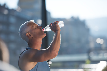 Image showing senior jogging man drinking fresh water from bottle