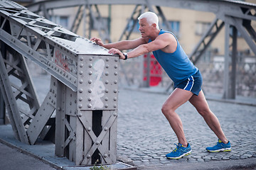 Image showing handsome man stretching before jogging