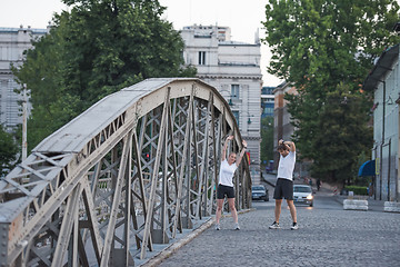 Image showing couple warming up and stretching before jogging