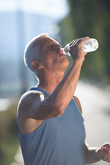 Image showing senior jogging man drinking fresh water from bottle