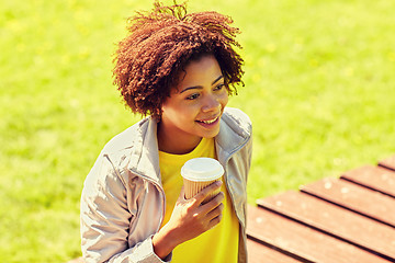 Image showing smiling african woman drinking coffee outdoors 