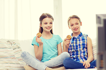 Image showing happy girls watching tv and eating cookies at home