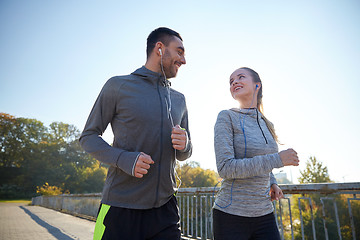 Image showing happy couple with earphones running outdoors