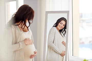 Image showing happy pregnant woman looking to mirror at home